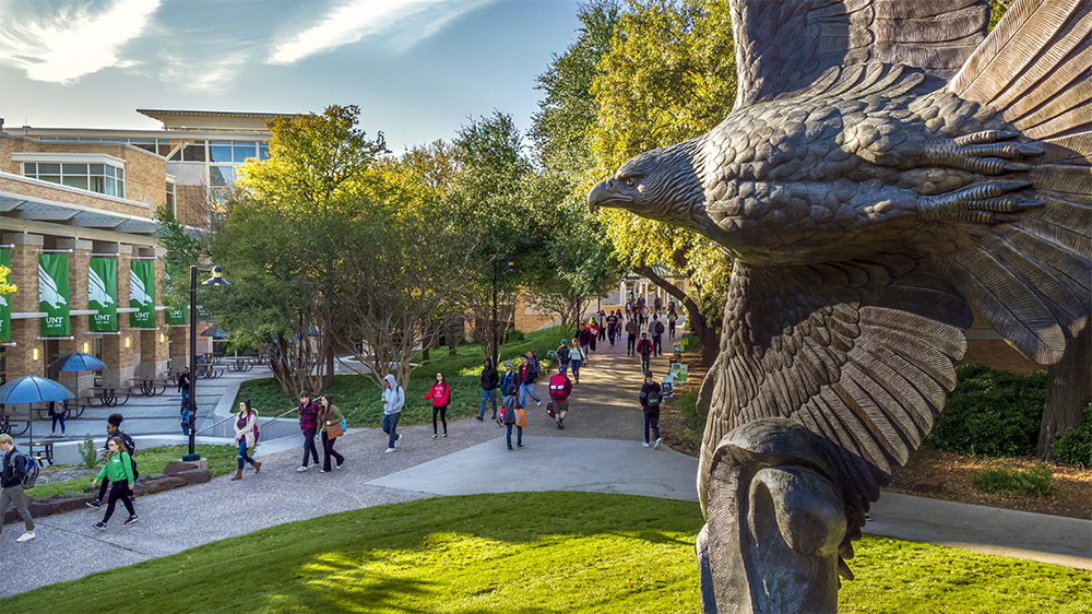 Eagle statue with students walking along on the sidealks